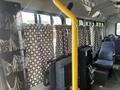 Interior of a 2012 Chevrolet Express showing fabric curtains on the windows a yellow pole and blue upholstered seats