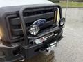 A 2015 Ford F-450 with a black front grille guard featuring PIAA lights and a winch attached to the front bumper