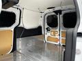 A 2016 Ford Transit Connect cargo van interior showing a spacious, metal floor with walls lined in plywood and a partition with a mesh window