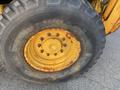 A close-up of a yellow Komatsu WB156PS-5 wheel showing the tread pattern and rust on the rim