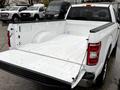 A 2018 Ford F-150 with an open white truck bed showcasing its spacious interior and textured flooring