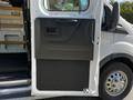The image shows the side door of a 2023 Ford Transit with a black handle and interior panel featuring a smooth surface and a door latch