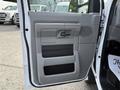 The interior door panel of a 2013 Ford Econoline featuring a gray finish with a handle and storage compartments