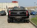 A black 2021 Ford F-350 SD parked with its rear facing the viewer showcasing its tailgate and dual rear wheels