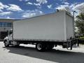 A 2020 Hino 338 truck with a large white cargo box and a flatbed rear is parked on a paved surface