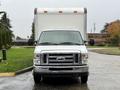 A 2013 Ford Econoline white cargo van with a box rear and clear headlights facing forward