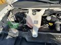 Engine compartment of a 2014 Chevrolet Express showing the coolant reservoir battery and various engine components