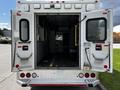 A 2013 Chevrolet Express ambulance with open rear doors displaying the interior and medical equipment setup