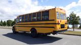 A 2014 Freightliner Thomas diesel school bus with a bright yellow exterior and black stripes, viewed from the rear with multiple windows and a high roof