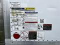 A 2018 Isuzu NRR truck with various safety instruction labels and caution signs displayed on its side panel