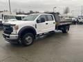 A 2021 Ford F-550 truck with a flatbed body painted in white with black wheel rims and a single cab design