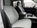 Interior view of a 2022 RAM 1500 Classic featuring two front seats in light gray upholstery and a center console with cup holders