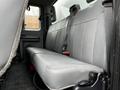 Interior view of a 2013 Ford F-650 showing a grey bench seat with seat belts in a cabin setting