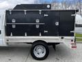 A 2007 Ford F-550 with a white cab and a black service body featuring multiple large storage compartments with metal latches on the side