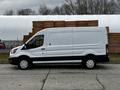 A white 2020 Ford Transit van with a black stripe along the lower side and five alloy wheels parked beside stacked wooden pallets