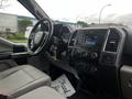 The interior of a 2017 Ford F-150 featuring a dashboard with a touchscreen display and various control knobs along with gray cloth seats