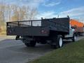 A white 2018 Ford F-450 SD truck with a flatbed and a black metal rail on the back, showcasing its dual rear wheels and a sturdy chassis