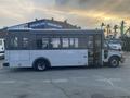 A 2017 Chevrolet Express bus with a white body and large windows, featuring a side entrance and equipped for passenger transport