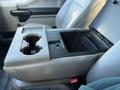 Center console of a 2020 Ford F-550 featuring two cup holders and a storage compartment