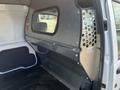 A 2010 Ford Transit Connect interior view showing a metal partition with a window and a rubberized floor surface