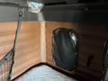 Interior of a 2022 Freightliner Cascadia showing brown leather-like wall panels a mesh storage net and a small window covered with a black flap