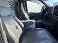 Interior view of a 2014 Chevrolet Express with two leather seats and a console in between featuring cup holders and storage compartment
