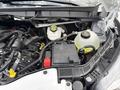 A close-up view of the engine compartment of a 2023 Ford Transit showcasing various components including the coolant reservoir and battery
