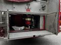 A 1991 Sutphen Deluge firetruck with an open compartment revealing a red engine and a white water tank