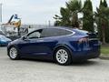 A blue 2020 Tesla Model X in profile view showcasing its sleek design and distinctive rear lights with five-spoke alloy wheels