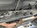 Underneath view of a 1962 Ford F-100 showing the chassis with bolts and exhaust system components visible