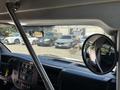A 2020 Chevrolet Express dashboard with a steering wheel and a side mirror showing nearby parked vehicles in the background