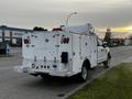 A white 2019 Ford F-350 SD truck with a service body and various tool compartments is parked on the street