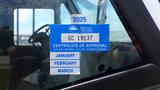 A blue certificate of approval sticker attached to a window of a 2011 Ford Econoline displaying the year 2025 and expiration information for January, February, and March