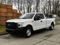 A white 2016 Ford F-150 truck with a crew cab and chrome front grille parked on a street