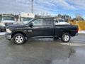 A black 2015 RAM 1500 pickup truck with a double cab and raised wheels parked on a surface with some snow