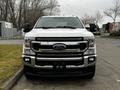 A white 2020 Ford F-350 Super Duty truck is parked facing forward with its chrome grille and large headlights visible