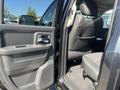 A 2011 RAM 1500 with the driver side door open revealing the interior featuring black leather seats and a spacious backseat area