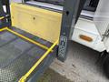 A 2010 Ford Econoline with a Ricon wheelchair lift extended and yellow safety straps in place on a metal platform