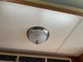 Ceiling light fixture with a brushed metal finish and a frosted glass dome in a recreational vehicle interior