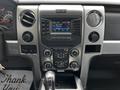 Interior dashboard of a 2014 Ford F-150 featuring audio controls and a digital display showing radio frequency and song information