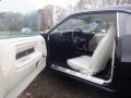 A 1974 Dodge Challenger with a black exterior and cream-colored interior featuring a vintage steering wheel and bucket seats