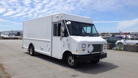 A white 2011 Ford Econoline delivery truck with a boxy shape and side windows parked on a pavement