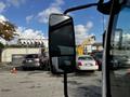 A 2016 Isuzu NPR truck with a large side mirror reflecting nearby vehicles and the surrounding area