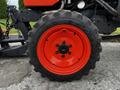 Close-up of a Kubota B2650 tractor tire featuring a black tread pattern and an orange wheel with a central bolt and smooth finish