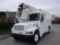 A 2002 International 4700 truck with a white body equipped with a raised bucket lift for overhead work