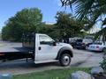 A white 2013 Ford F-450 Super Duty truck with a flatbed parked on a driveway