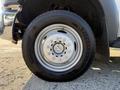 Close-up of a wheel from a 2014 Ford F-550 showing a silver metallic rim with multiple bolts and a black tire with visible tread patterns and brand logo