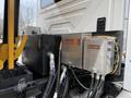 Close-up of hydraulic components on a 2016 International 7600 including metal tanks and control boxes labeled Rexroth with various hoses connected
