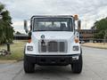 A white 1998 Freightliner FL80 truck with a prominent grille and headlights is facing forward with safety lights on the roof and a spotlight mounted on the front bumper