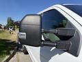 A close-up of the side mirror of a white 2017 Ford F-350 SD showing its black housing and integrated turn signal light